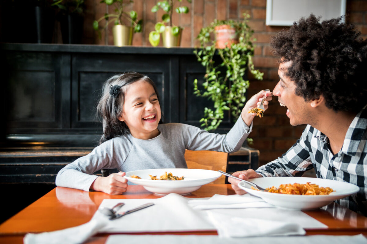daughter feeding dad at restaurant