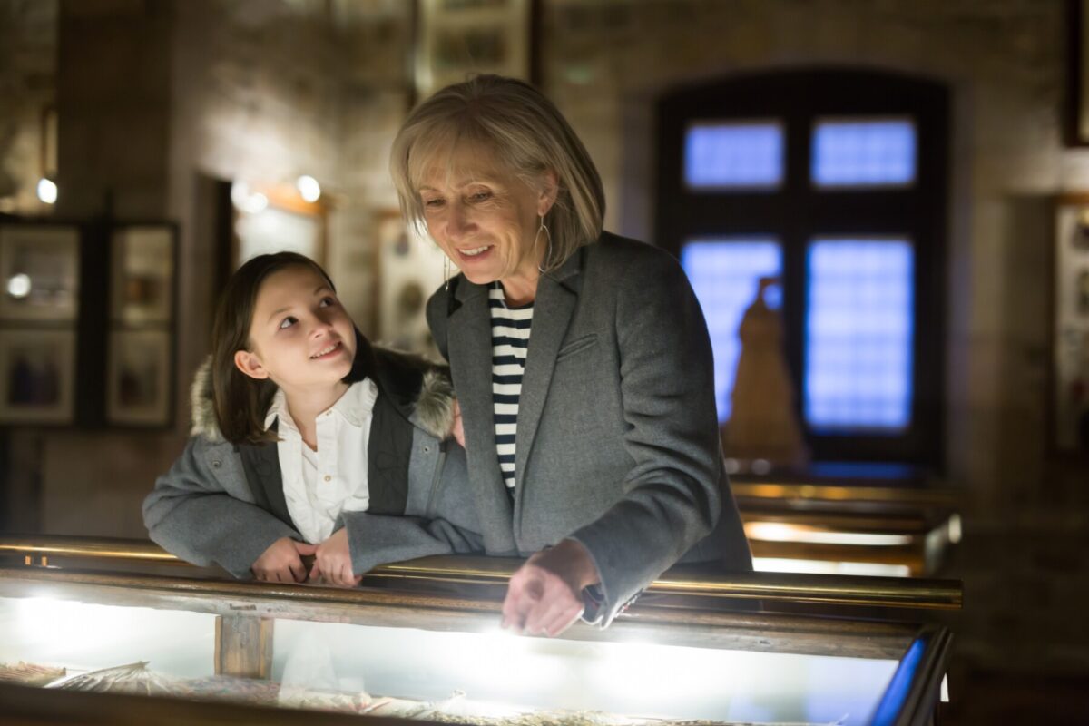 older woman and young girl looking at museum exhibit together