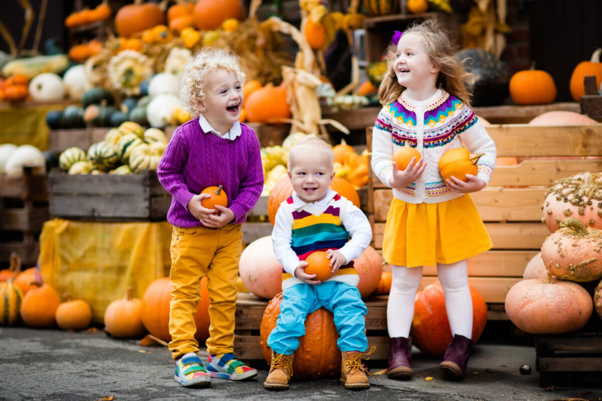 kids smiling and holding pumpkins