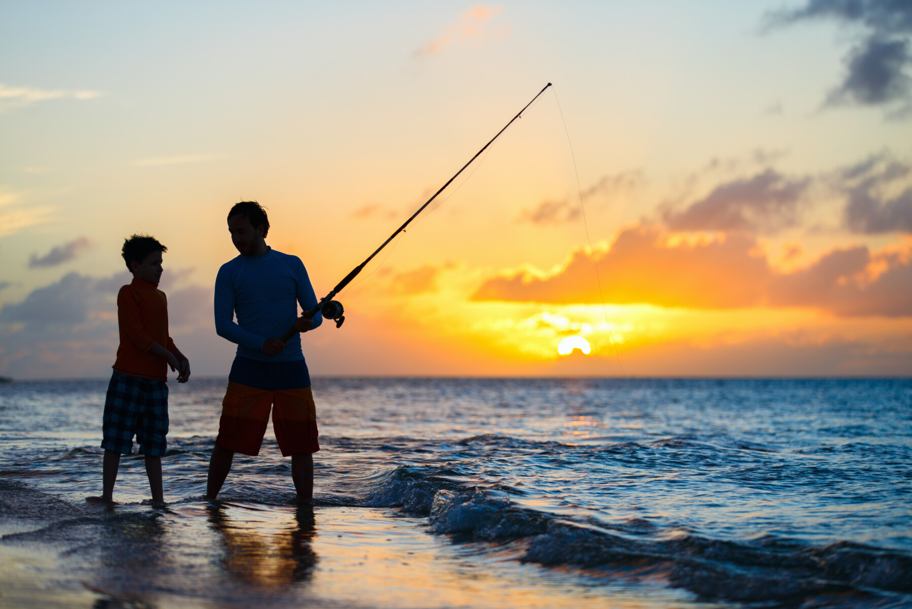 father and son fishing in a sunset