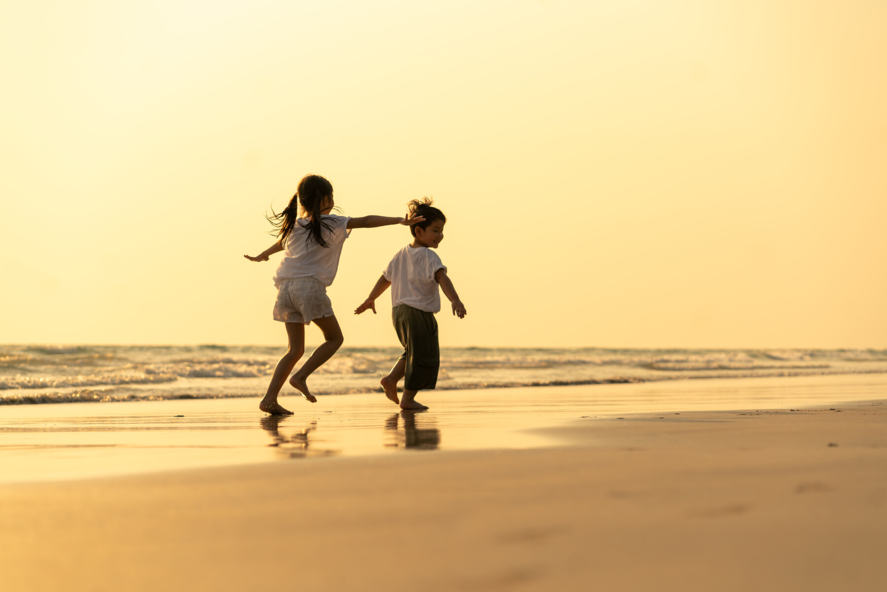 kids running on the sand at sunset